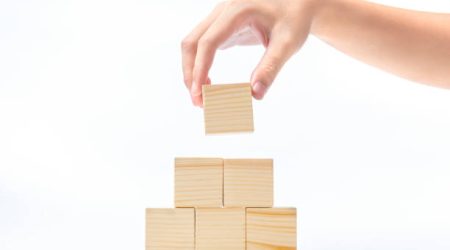 Hand build a pyramid from a wooden block isolated over white background